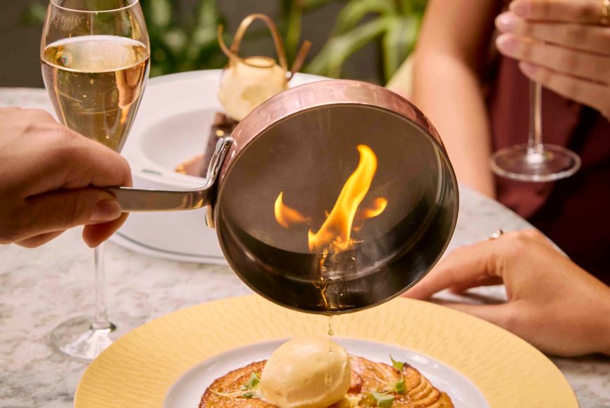 oil being poured on a meal, champaign glasses behind it